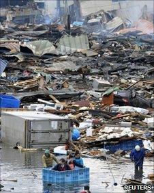 People use a floating container to escape floodwaters after a tsunami in Kesennuma, Japan, on 12 March, 2011.