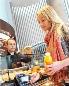 Woman using a mobile to pay for a drink