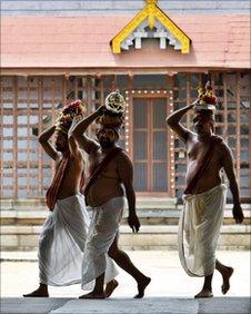 Hindu priests walk in front of a building housing the vaults at the 16th-century Sree Padmanabhaswamy Temple complex in Trivandrum, India, Tuesday, July 5, 2011.