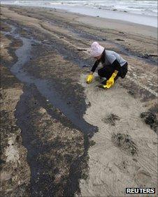 Volunteers remove fuel oil from the stricken container ship Rena that washed up beaches at Papamoa, near Tauranga