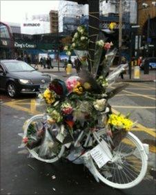 A ghost bike tribute and flowers where a cyclist died near King's Cross