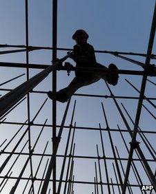 Worker stands on scaffolding for new shopping mall in Hefei, Anhui province, on 27 November 2011