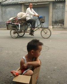 A young girl sits in a cardboard box on the edge of a road in Beijing (file photo)