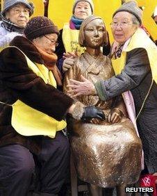 Former South Korean comfort women (wearing yellow vests) pose with the Peace Statue symbolising a wartime sex slave at the 1,000th weekly anti-Japan rally in front of the Japanese embassy in Seoul