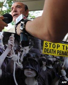 Alan Shadrake, a freelance journalist and author displays the campaign poster while talking to reporters outside the Supreme court in Singapore on 27 May, 2011