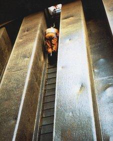 A deep rummage officer climbing a ladder in a carriageway hold of a bulk carrier