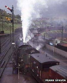 Northbound and southbound Anglo-Scottish freight trains wait to change footplate crews at Hawick in the summer of 1964. This was almost exactly the half-way point between Edinburgh and Carlisle, and was the typical change-over location for train crew until Hawick locomotive depot closed, with the virtual demise of steam, in January 1966.