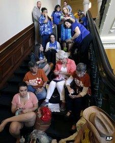 Supporters and opponents of an abortion bill pass time as they wait in line outside the Texas Senate chambers as he final vote by the Senate is expected to begin, 12 July 2013