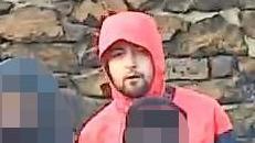 A man with a short brown beard, wearing a red hoodie with the hood up. 