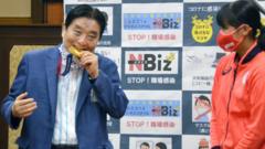 El alcalde Takashi Kawamura mordiendo la medalla de oro de Miu Goto.
