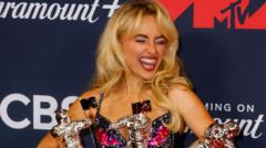 Popstar Sabrina Carpenter pulling a silly face as she holds awards at a red carpet ceremony