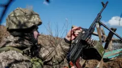 A Ukrainian serviceman holds a machine gun at a town in Donestsk