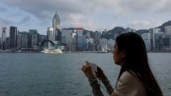 一位女士在香港尖沙咀海旁眺望维多利亚港与香港岛北岸风光（2/5/2023）