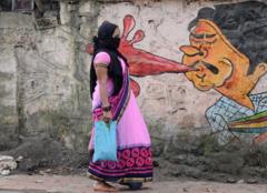 Мумбайда граффитинин жанынан өтүп бараткан аял. Көркөм чыгармалар коомдук жайларда түкүрүүнүн коркунучу жөнүндө маалымдоо үчүн колдонулган.