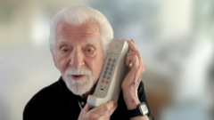 Марти Купер с телефоном, при помощи которого он совершил исторический первый звонок