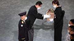 Perdana Menteri Jepang Fumio Kishida menyerahkan abu PM Shinzo Abe kepada istrinya , Akie Abe dalam upacara pemakaman di Tokyo.. 