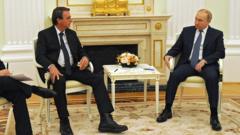 Bolsonaro e Putin sentados lado a lado em um salão branco com uma lareira dourada no Kremlin