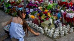devojcica ostavlja svece i cvece za zrtve pucnjave