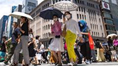Personas caminan por las calles de Tokyo con sombrillas para protegerse del sol.