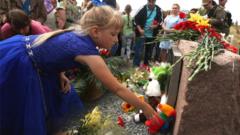 People lay flowers at the monument to the victims of the Malaysia Airlines flight MH17 crash, in the village of Grabovo, Ukraine, 17 July 2017