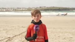 Child Max looking at camera stood on a beach.