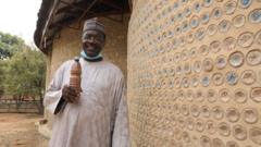 Yahaya Ahmed by di seide of di plastic bottle house