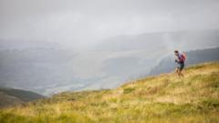 Rhedwr yn mynd lawr y bryn trwy'r glaw