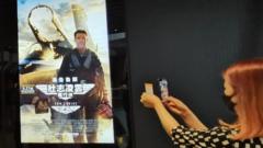 香港一家电影院门口一位女性观众在拍摄"《壮志凌云：独行侠》的招贴画