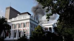 Smoke billows from the roof of a building at the South African Parliament precinct in Cape Town on 2 January 2022, during a fire incident
