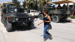 A woman walks past army soldiers outside a sports hall where ballot boxes and election material are collected to be distributed to polling stations, ahead of Sunday's presidential election in Tunis (14 September 2019)