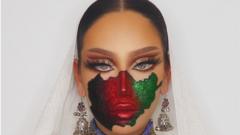 An Afghan female model with make-up of the Afghanistan flag painted on her face