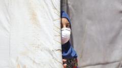 A Syrian girl wearing a medical mask as a precaution against coronavirus is seen at a refugee camp in Idlib