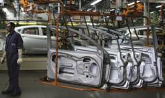 Trabalhador e portas de carro em linha de produção de indústria automotiva