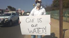 Protester holding a sign saying "give us our water"