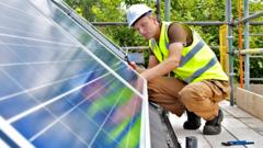 Stock image of a workman fixing solar panels to a house