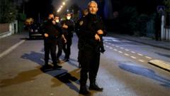 Cinco policiais enfileirados, o primeiro empunhando arma, em rua à noite