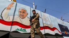 Um membro das forças iraquianas passa por um mural que retrata o Papa Francisco acenando ao lado de uma bandeira nacional iraquiana, em Bagdá