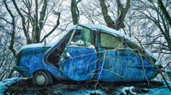 An abandoned blue car in an icy forest