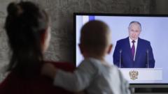 A woman holds her child as she watches the televised address by Russian President Vladimir Putin before the Federal Assembly, in Moscow, Russia, 21 February 2023. '