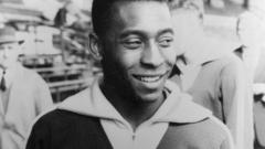 Em foto preto e branco, Pelé sorri, com casaco do Brasil