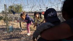 Famílias de imigrantes, incluindo crianças, passando por baixo de cerca para cruzar a fronteira do México para os Estados Unidos para solicitar asilo em 08 de maio de 2023 em El Paso, Texas