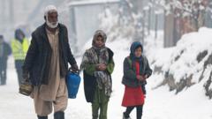 A man carrying gas canisters walks next to children along a street during snow fall in Kabul on January 11, 2023.