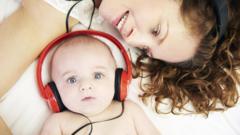 Bebê com fones de ouvido ao lado de sua mãe