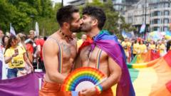 Men kissing in front of a Pride flag