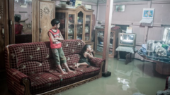 Dos niños miran TV en una habitación inundada.