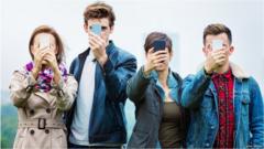 4 people holding their smartphones in front of their faces