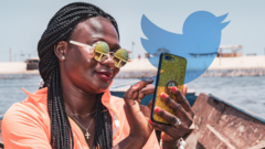A woman in Ghana using a phone with the Twitter logo in the background