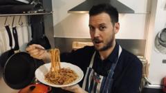 Edwin eating pasta in his kitchen