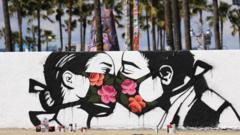 Graffiti by artist Pony Wave depicting two people kissing while wearing face masks, Venice Beach, California, USA - March 2020