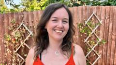 A white woman with brown hair smiles in the garden looking at the camera.